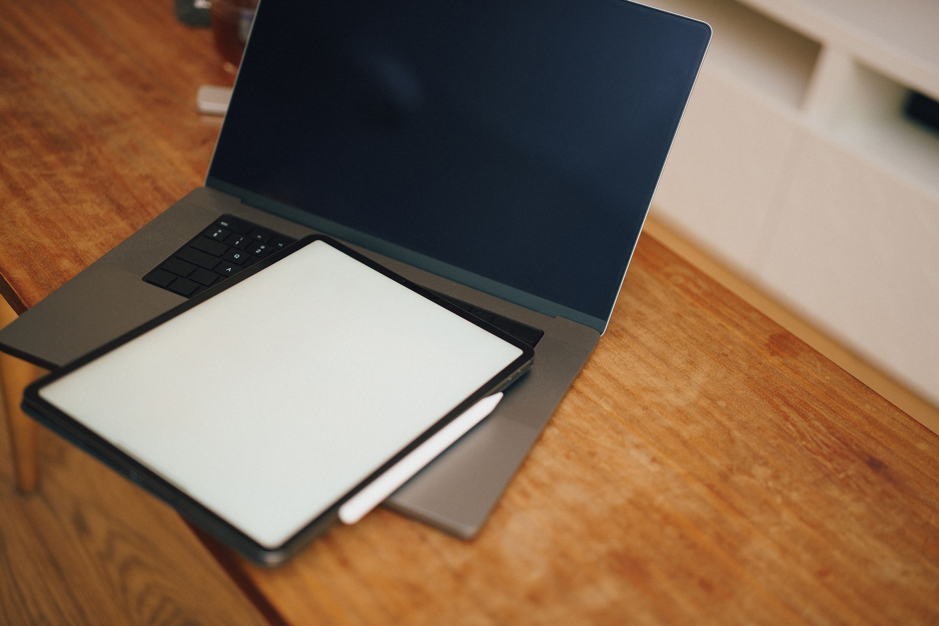 Laptop e tablet gráfico sobre mesa de madeira, representando o uso de ferramentas digitais no design gráfico
