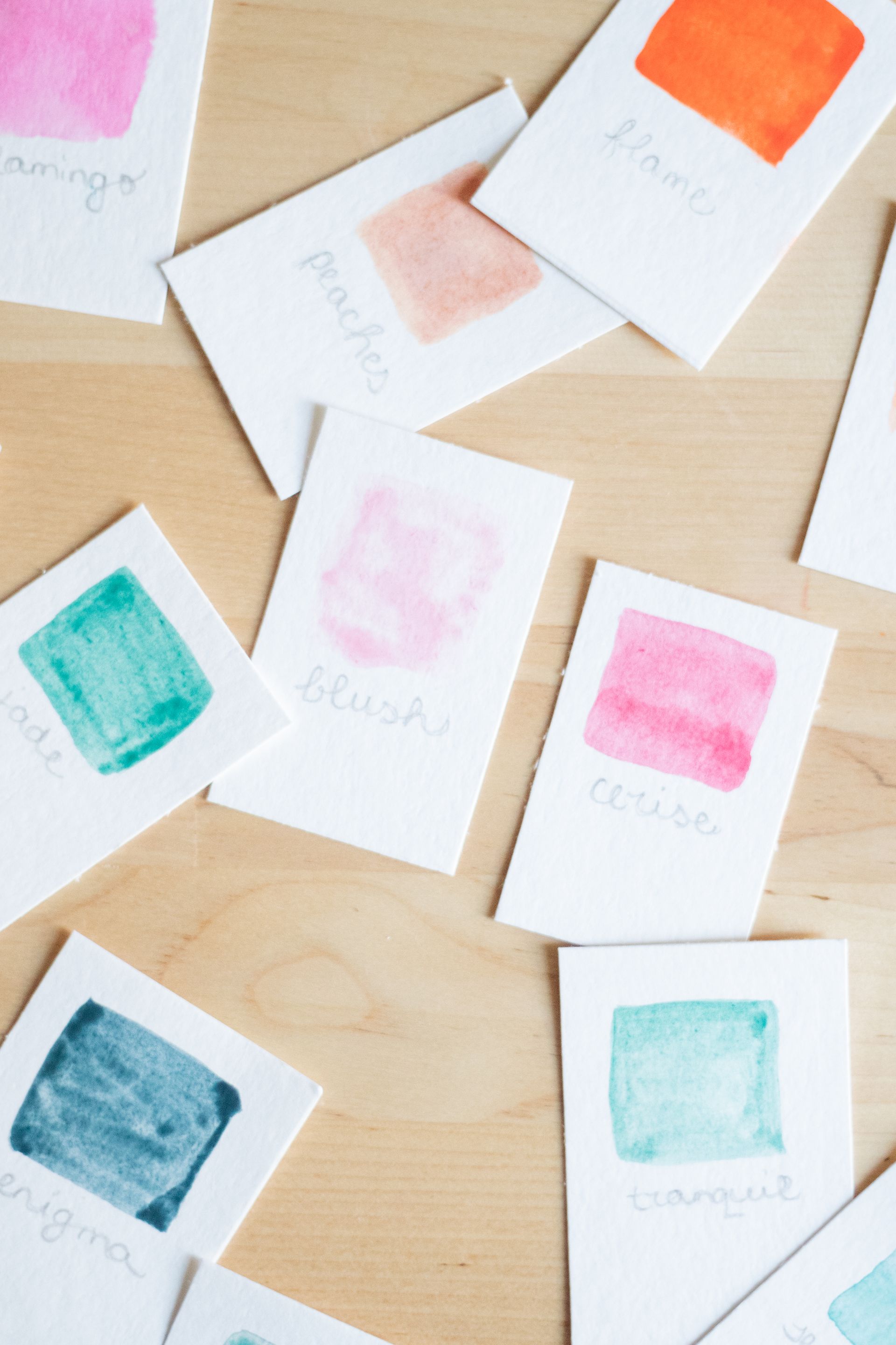 Amostras de cor em aquarela sobre mesa de madeira clara, representando paleta de cores e tendências de design gráfico